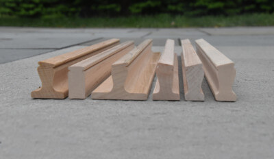 Six custom wood moulding profiles displayed vertically, showcasing dimensional shaping for bulk production.