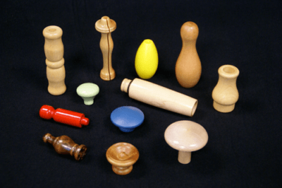 Shaped and Turned Wood Components in Various Sizes and Finishes Assorted shaped and turned wood components in different sizes, finishes, and wood species, arranged on a black surface.