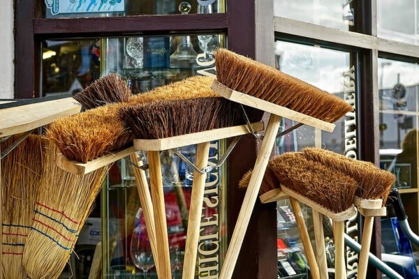 Custom Wooden Broom Handles for Bulk and Specialty Applications Multiple wooden broom handles with attached sweeping heads placed upright in a row.