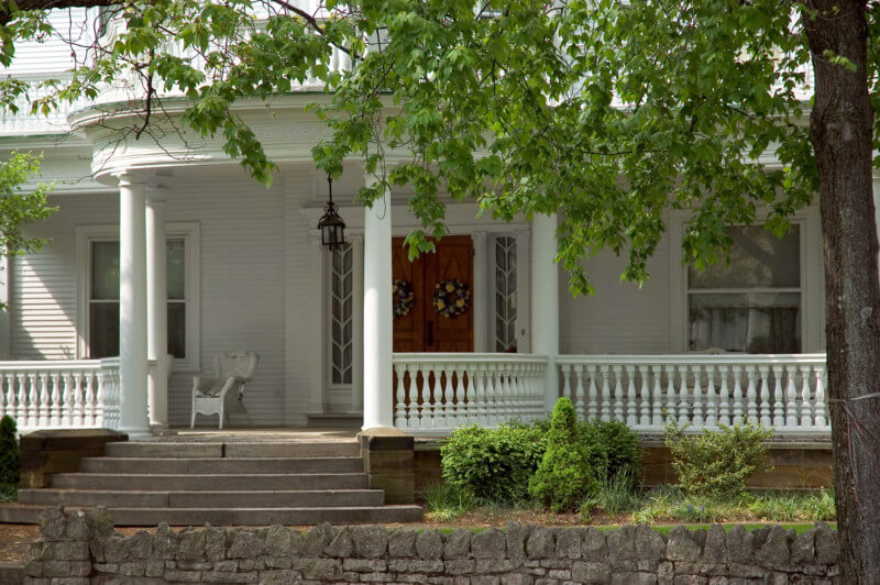 Victorian Front Porch with Custom Wood Columns and Spindles Victorian-style front porch featuring turned wood columns and decorative spindles on a large home.