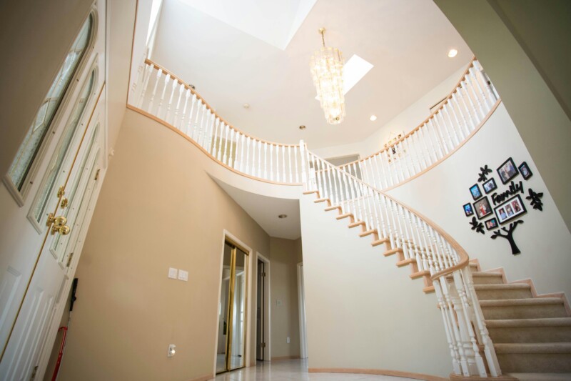 Replacing Wood Stair Balusters in Grand Curved Entryway Curved staircase with white wood stair balusters and natural handrail in residential entryway.