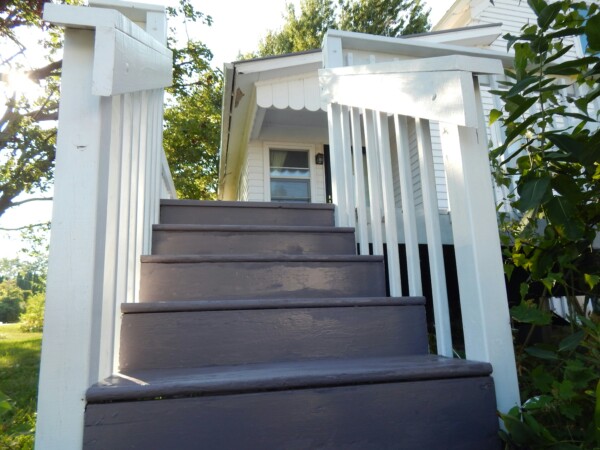 Painted wooden deck steps with white railings and gray stair treads.