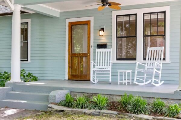 Craftsman Porch with White Wood Columns and Rocking Chairs Craftsman-style front porch with white wood columns, rocking chairs, and a natural wood front door.