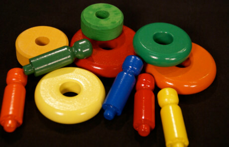 Assorted painted wooden toy parts with child-safe enamel finishes in various bright colors.