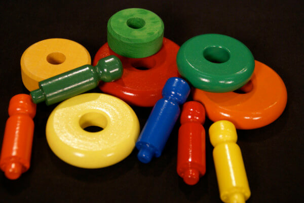 Assorted painted wooden toy parts with child-safe enamel finishes in various bright colors.