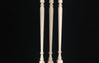 Three custom interior wood balusters with square ends for stair rail installation.