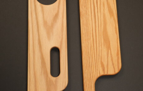 Custom-shaped wood chair arms CNC routed for furniture manufacturing applications.