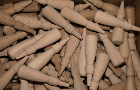 Rows of custom wood handles produced in bulk using automated lathes for high-volume manufacturing.