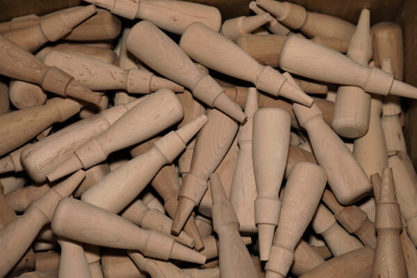 Rows of custom wood handles produced in bulk using automated lathes for high-volume manufacturing.