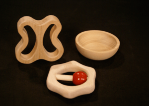 Three custom CNC-routed wood components shaped for use as toy parts, brush blocks, or tool handles.