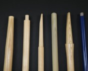 Assorted long wood tool handles stacked in rows, custom-machined for shovels, rakes, brooms, and more.