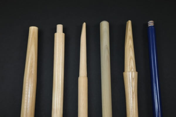 Assorted long wood tool handles stacked in rows, custom-machined for shovels, rakes, brooms, and more.