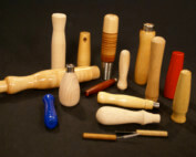 Custom turned wood handles in various sizes, shapes, wood species, and finishes, arranged side by side for display.