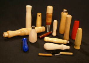 Custom turned wood handles in various sizes, shapes, wood species, and finishes, arranged side by side for display.