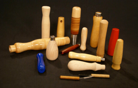 Custom turned wood handles in various sizes, shapes, wood species, and finishes, arranged side by side for display.