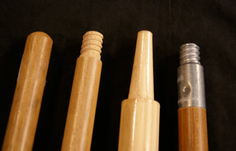 Four wooden broom and mop handles with varied end types including tenoned, tapered, and threaded attachments.