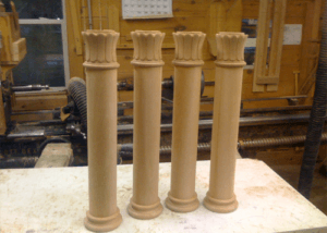 Four custom wood columns with decorative details in various sizes and finishes.