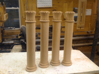 Four custom wood columns with decorative details in various sizes and finishes.