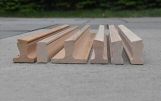 Six custom wood moulding profiles displayed vertically, showcasing dimensional shaping for bulk production.