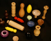 Assorted custom wood turnings in multiple shapes, sizes, finishes, and colors, displayed on a surface.