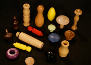 Assorted custom wood turnings in multiple shapes, sizes, finishes, and colors, displayed on a surface.