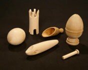 Assorted custom wood turnings with secondary operations including drilling and slotting, laid out on a surface.