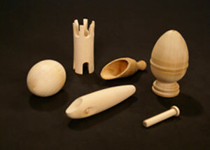 Assorted custom wood turnings with secondary operations including drilling and slotting, laid out on a surface.