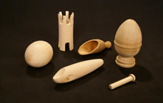 Assorted custom wood turnings with secondary operations including drilling and slotting, laid out on a surface.