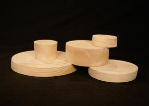 Three custom wooden bungs designed for sealing paper tubes in shipping and packaging applications.