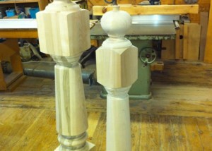 Two custom wooden newel posts with traditional profiles used for stair rail support and decorative architecture.