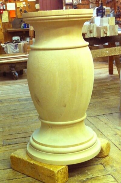 Custom turned wooden pedestal column for supporting tables, kitchen islands, or architectural elements.