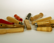 A variety of small wooden tool handles with grooves, beaded grips, and different finishes, custom manufactured for bulk orders.