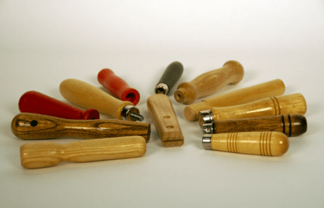 A variety of small wooden tool handles with grooves, beaded grips, and different finishes, custom manufactured for bulk orders.