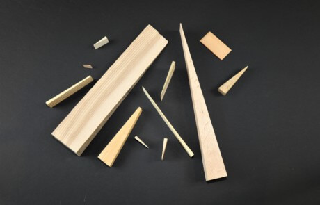 Assorted wooden wedges in various sizes and thicknesses made for industrial and utility applications.