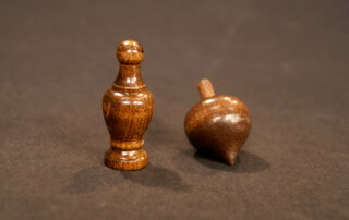 Two stained wooden finials on display, showcasing custom wood turning options for bulk and small orders.