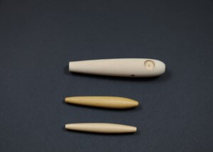 Three unfinished wooden fishing lure bodies designed for custom tackle production.