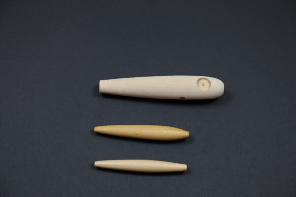 Three unfinished wooden fishing lure bodies designed for custom tackle production.