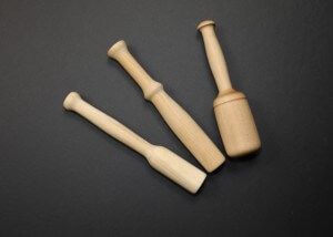 Three custom wooden muddlers in different shapes made from natural hardwood.