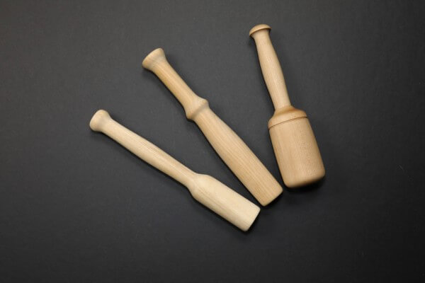 Three custom wooden muddlers in different shapes made from natural hardwood.
