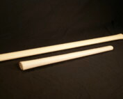 Several custom-shaped hickory wood handles for sledgehammers, axes, and hammers arranged on a work surface.