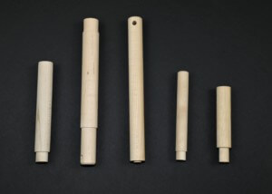 Five custom wood dowels with tenoned ends displayed on a black background, used for precision assembly in manufacturing.