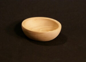Custom small turned wooden bowl made from light-colored hardwood, displayed on a neutral background.