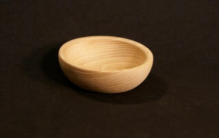 Custom small turned wooden bowl made from light-colored hardwood, displayed on a neutral background.