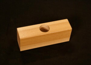 Custom moulded wood block with a precision-drilled hole for specialized applications.