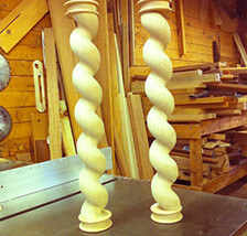 Two custom wooden porch posts with spiral rope twist design, shown upright.