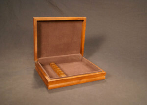 Custom wooden box with a hinged lid, felt-lined interior, and precision-cut inserts for secure item placement.