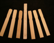 Stack of custom wood paint paddles in various thicknesses and lengths.