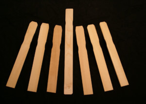 Stack of custom wood paint paddles in various thicknesses and lengths.