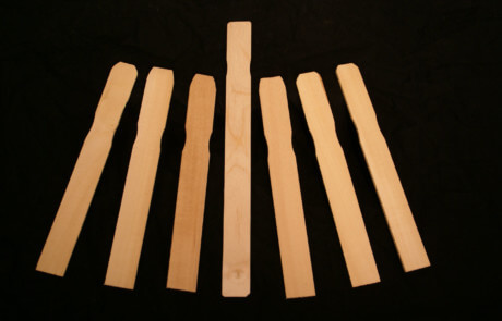 Stack of custom wood paint paddles in various thicknesses and lengths.