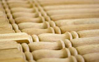 Multiple turned wood balusters lined up, each with detailed profiles for use in staircases or railings.